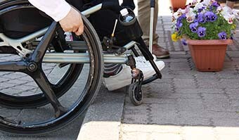 Image: Photograph of person in a wheelchair attempting to cross a difference in surface level of several centimeters outdoors on a general road.