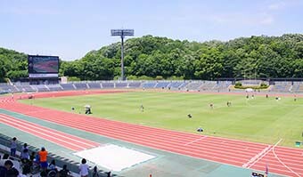 Image: Overall view of the Machida Stadium in Nozuta Park, Machida City, Tokyo, with the blue sky above.