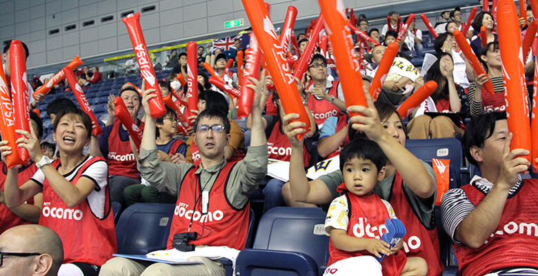 Image: Supporters decked out in bright DOCOMO red cheering on swimmer Takuro Yamada