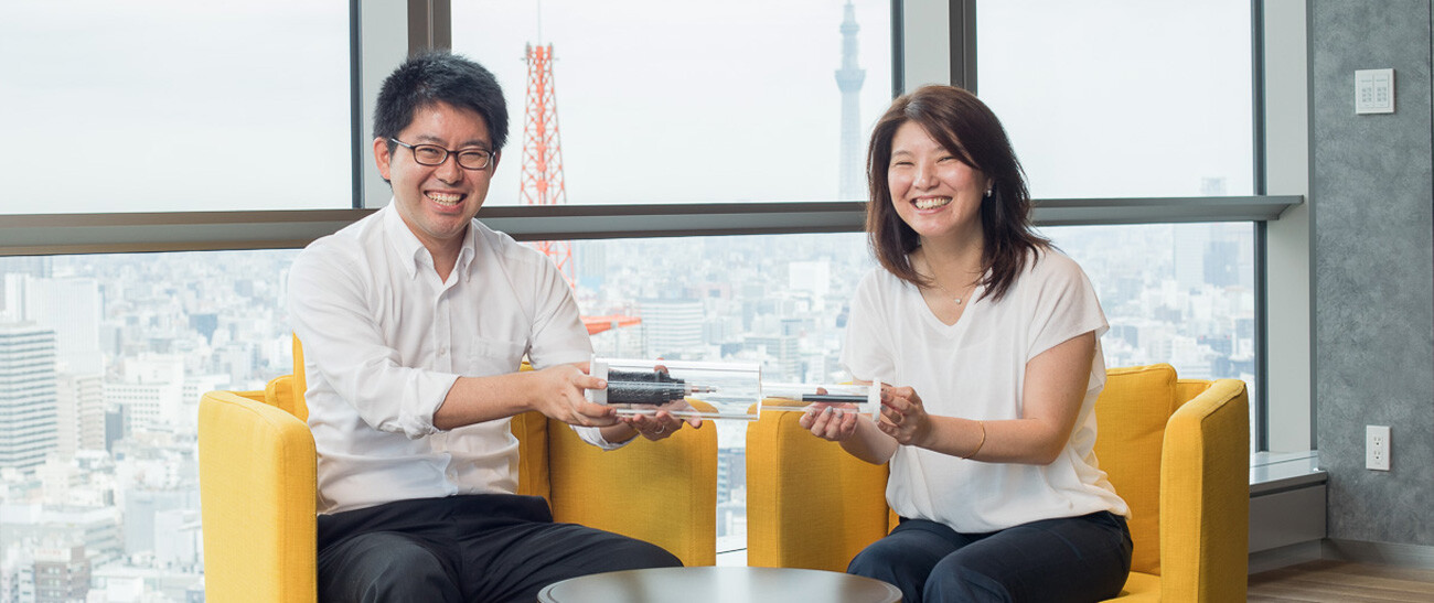 Image: Photograph of Mr. Sakairi (left) and Ms. Kanzaki (right) smiling as they hold a section of cable