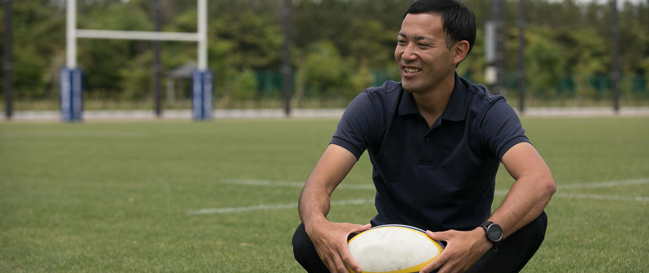 Image: Mr. KAWAHARA holding a rugby ball while talking