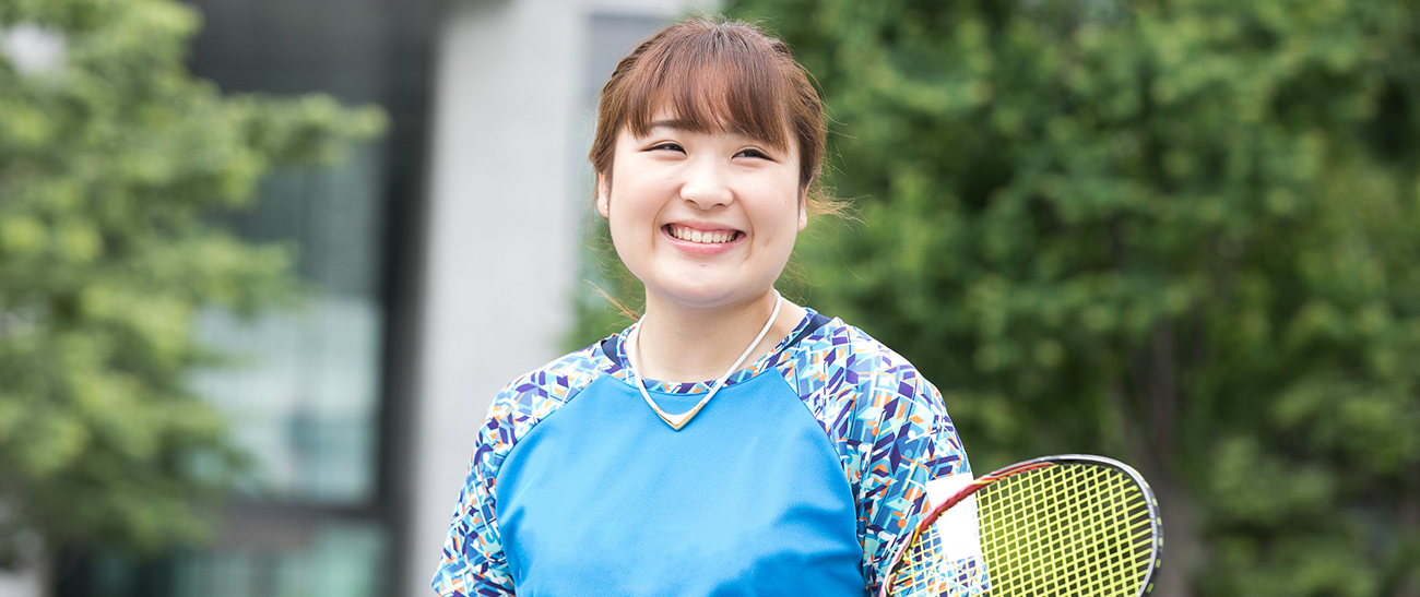 Image: Ms. SATOMI smiling happiily as she holds a badminton racquet