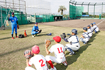 写真：NTT西日本硬式野球部によるふれあい野球教室で、グラウンドで選手の説明を聞く子どもたちの様子