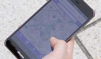 画像：バリアフリーマップを表示するスマートフォンの写真。屋外で男性が操作している姿の手元のアップ。